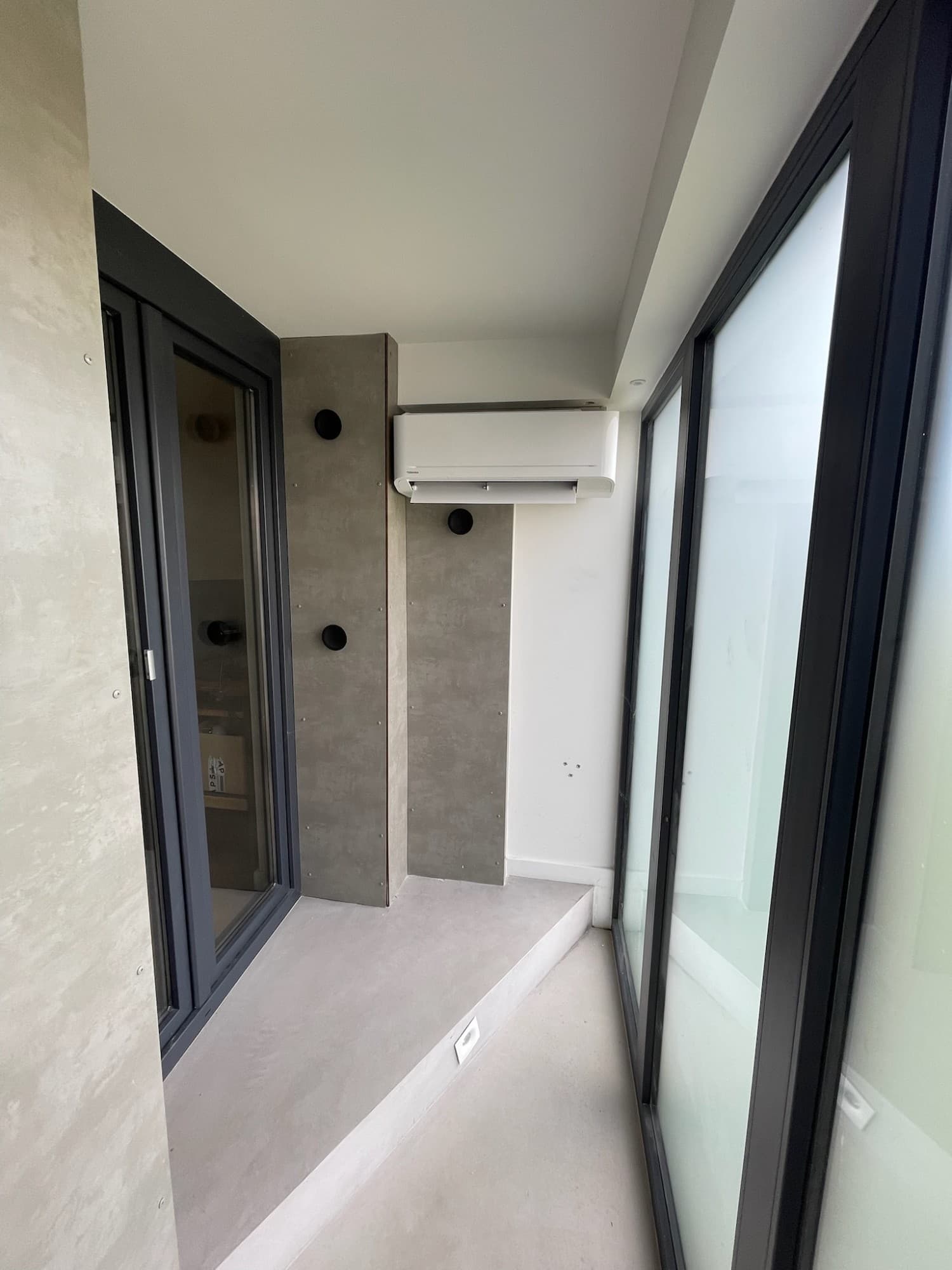 Mono-split Toshiba en loggia d'appartement haut de gamme — finitions béton ciré, intégration architecturale
